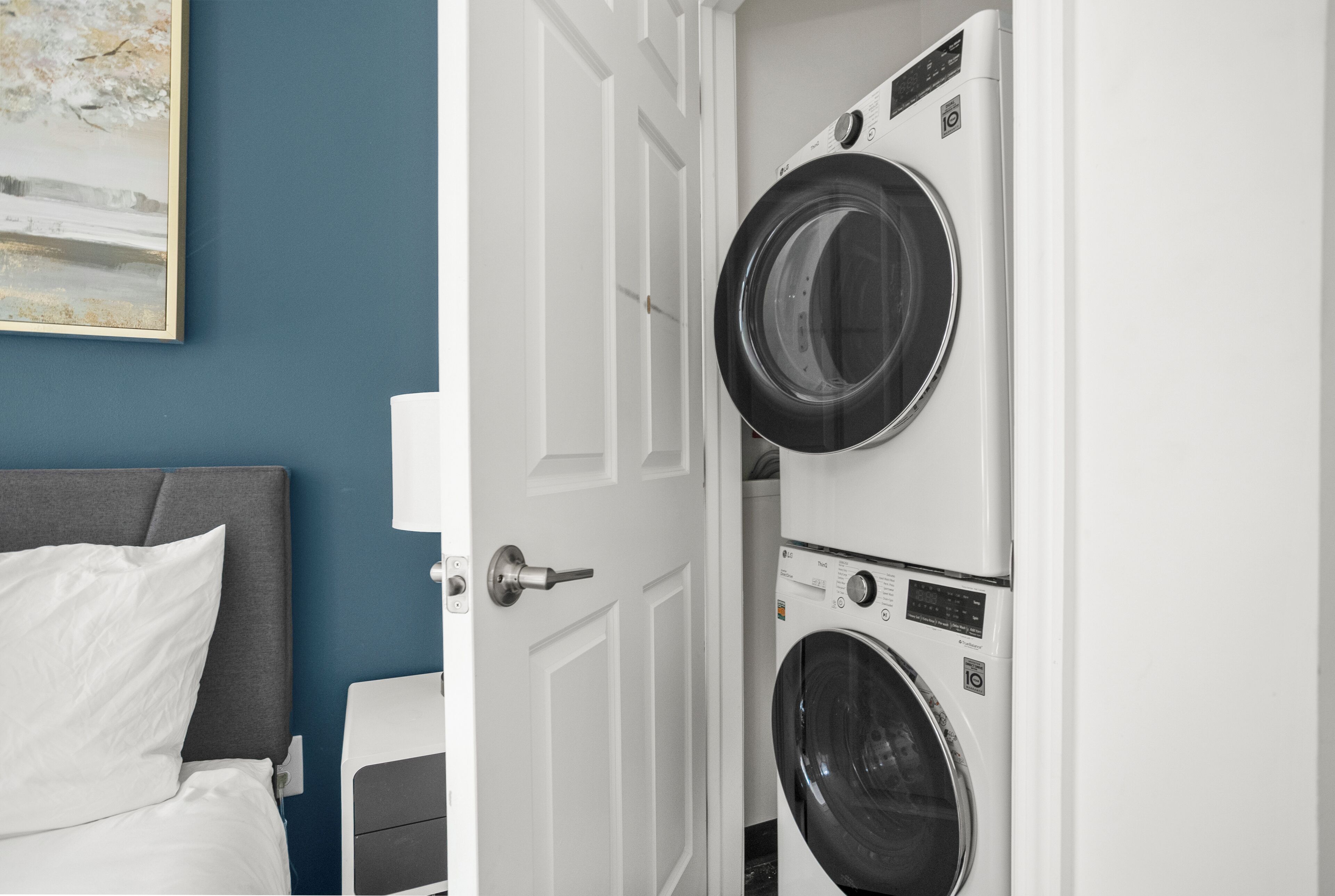 A hotel room with a bed, a nightstand, and a wall-mounted washing machine.