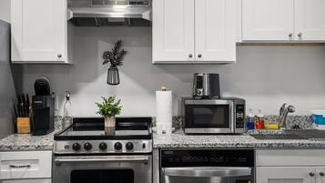 A modern kitchen with white cabinets, a stainless steel stove, a microwave, and a dishwasher.
