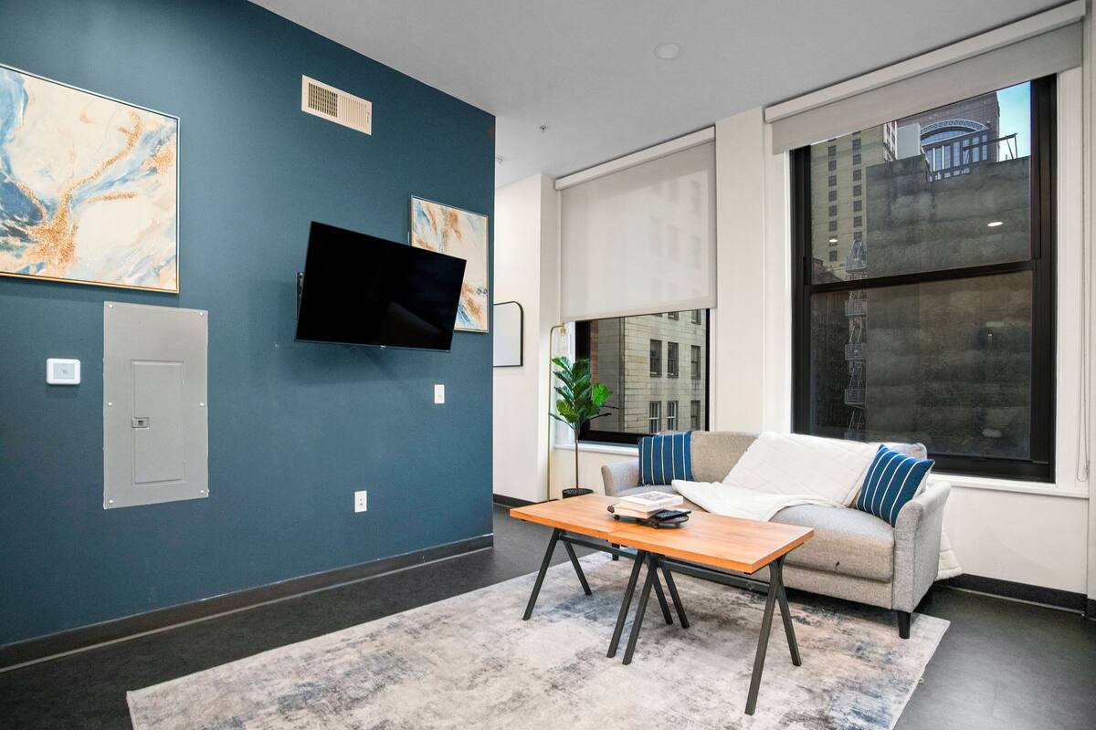 Un salon moderne avec un canapé, une table basse et un téléviseur à écran plat fixé au mur.