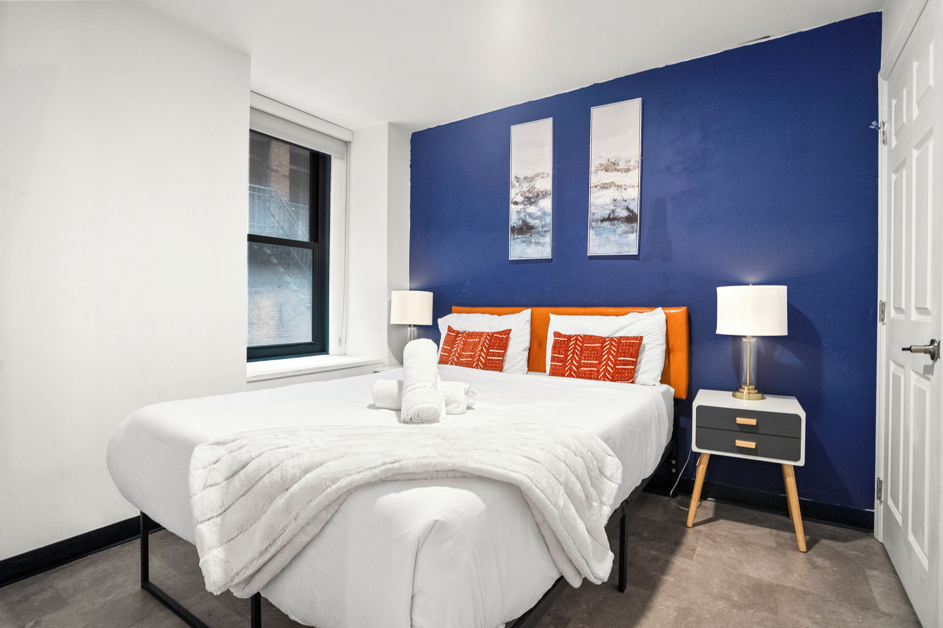 A modern bedroom with a large bed, two bedside tables, and a window.