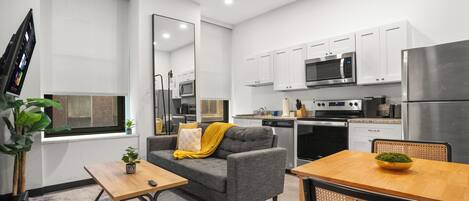 A modern kitchen with white cabinets, a microwave, and a stainless steel refrigerator.