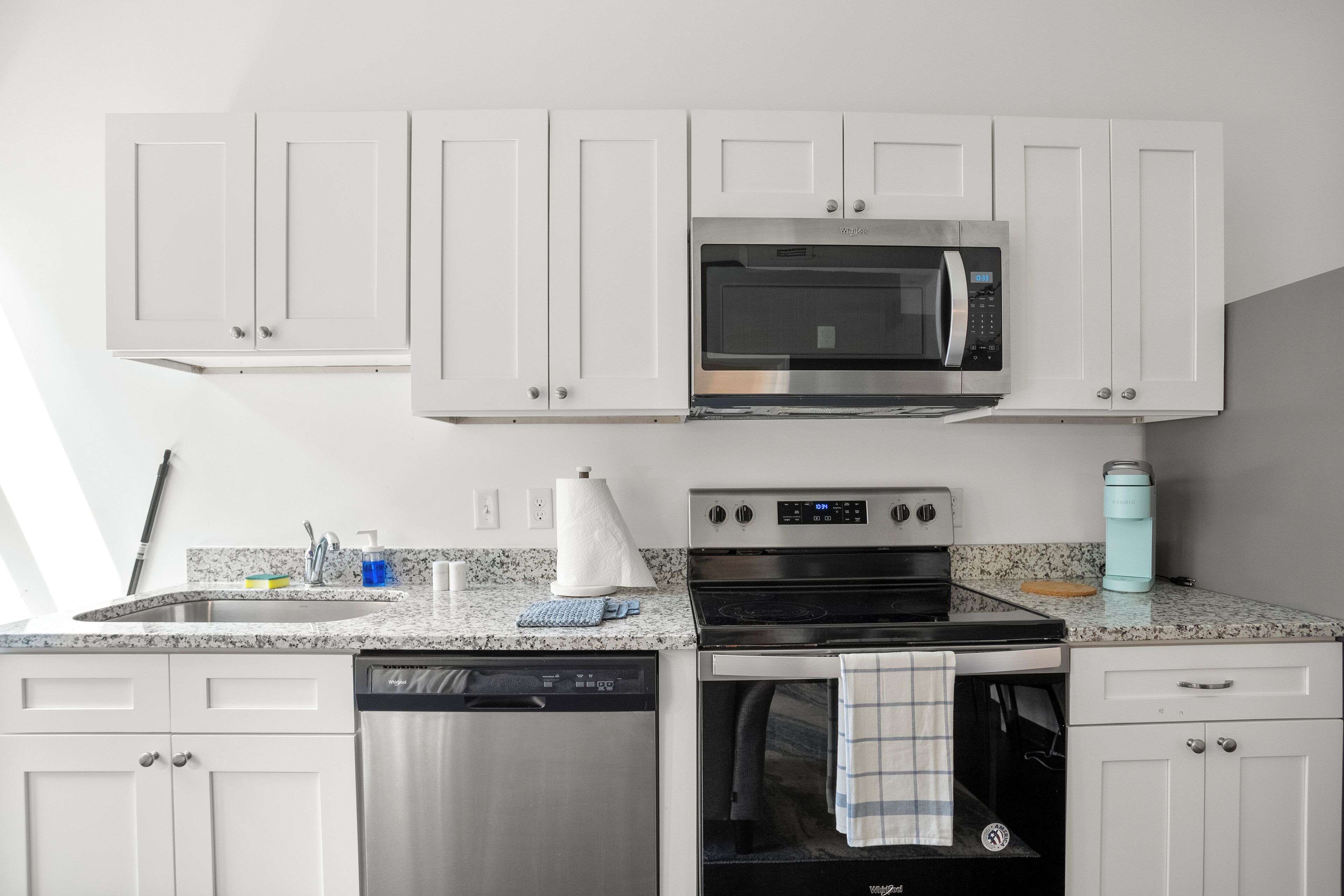 A modern kitchen with white cabinets, a built-in microwave, a dishwasher, and an oven.