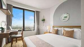 A modern hotel room with a large bed, a desk, and a view of the city. - Tenui by Kozystay - Tanjung Barat (Jakarta)