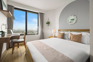 Relax in a spacious room with a large bed, desk, and city view.