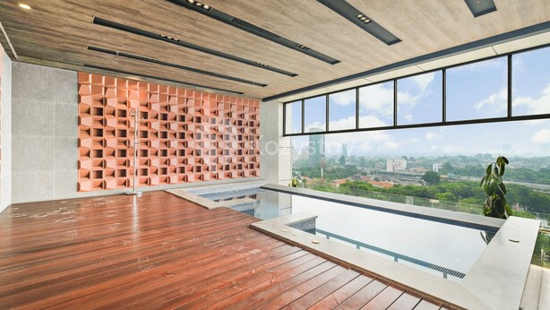 A spacious indoor area with a wooden floor, a pool, and a view of a cityscape through large windows. - Tenui by Kozystay - Tanjung Barat (Jakarta)
