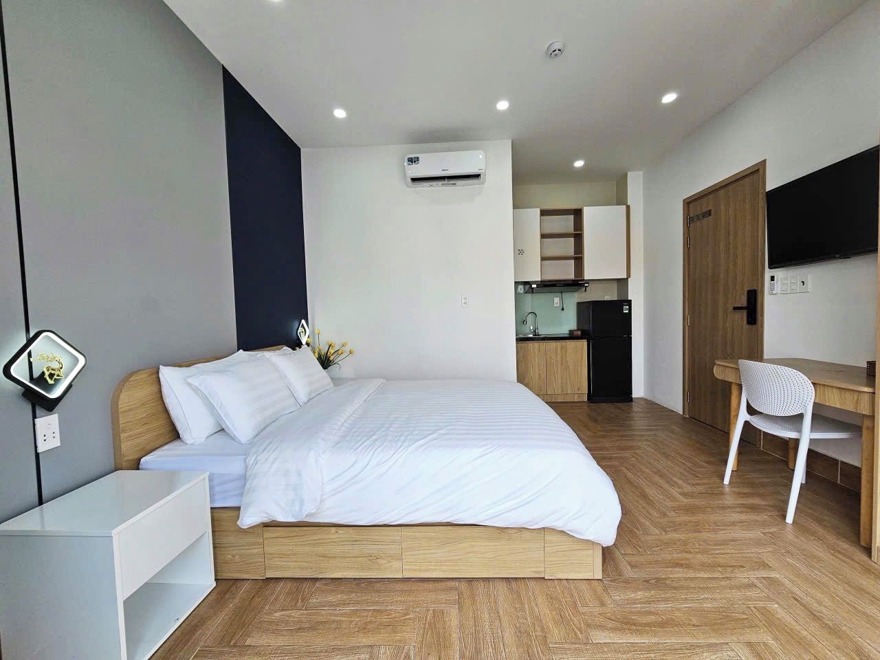 A modern bedroom with a bed, bedside table, and a desk with a chair.