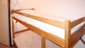Una cama litera con estructura de madera y ropa de cama blanca.