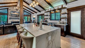 A modern kitchen with a large island, bar stools, and a stone fireplace. - Fire and Ice/Northstar Resort Truckee, CA (Truckee)