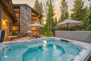A hot tub with a stone wall and a patio area with outdoor furniture.