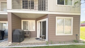 Ein zweigeschossiges Haus mit überdachter Terrasse, einer Schiebetür und einem kleinen Sitzbereich im Freien.