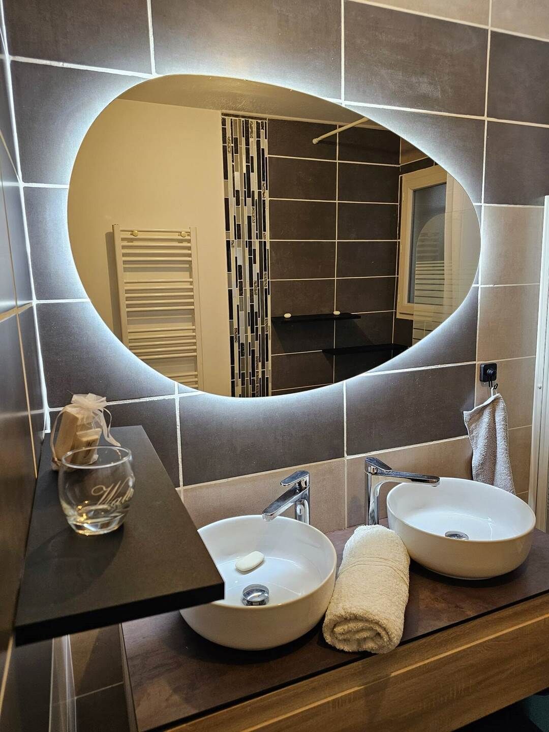 Un baño con dos lavamanos, un espejo y un perchero para toallas.