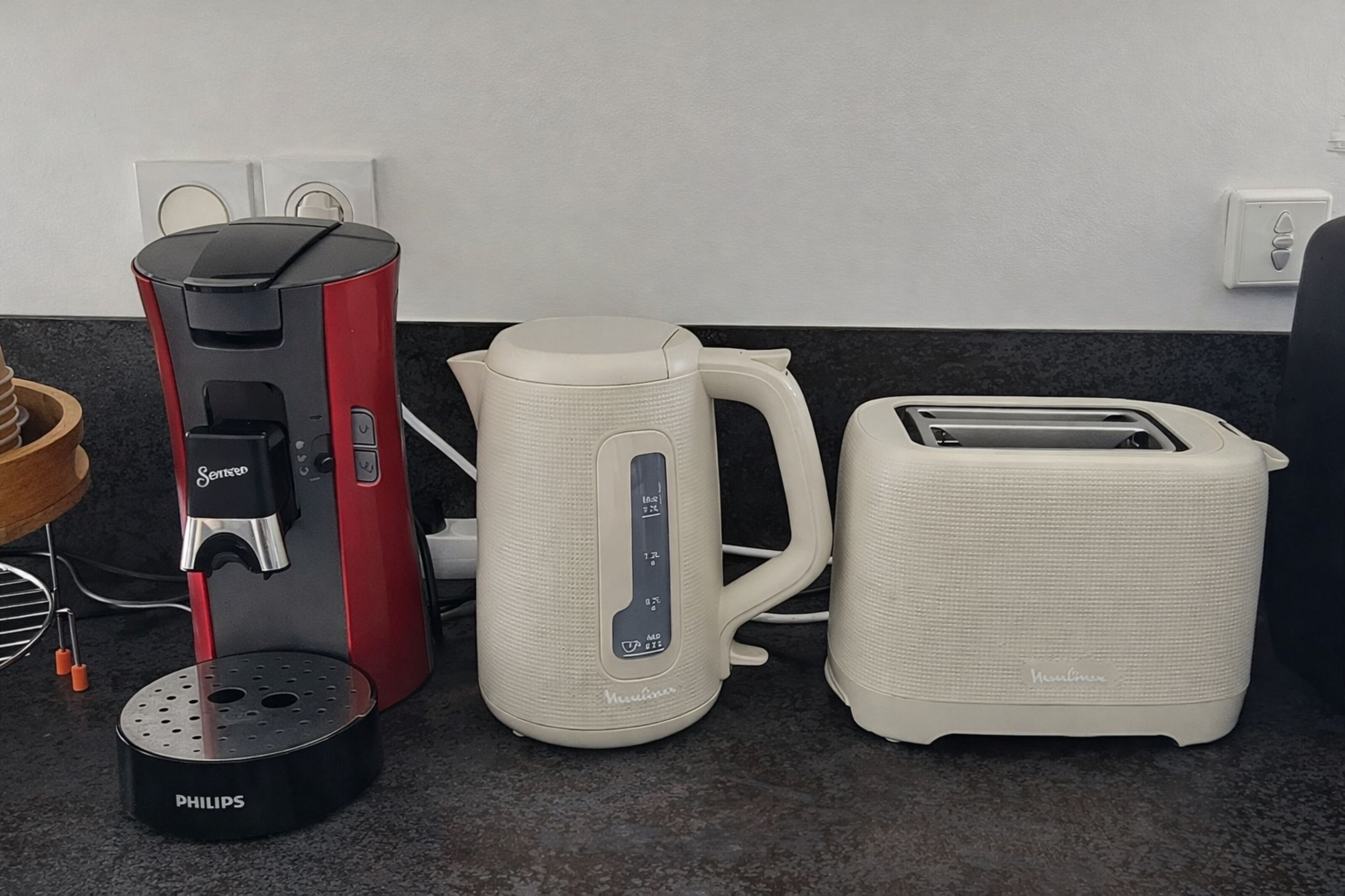 Eine Küche mit einer roten und schwarzen Kaffeemaschine, einem weißen Wasserkocher und einem weißen Toaster.