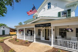A white building with a porch, an American flag, and a sign reading 'The Legacy Inn.'