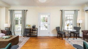 A room with a wooden floor, a chandelier, a dining table with chairs, a sofa, and a cabinet with wine glasses. - Charming suite w/ TV & patio (Luray)