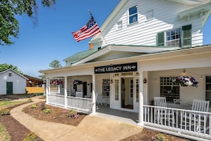 Een wit gebouw met een veranda, een Amerikaanse vlag en een bord waarop staat 'The Legacy Inn'.