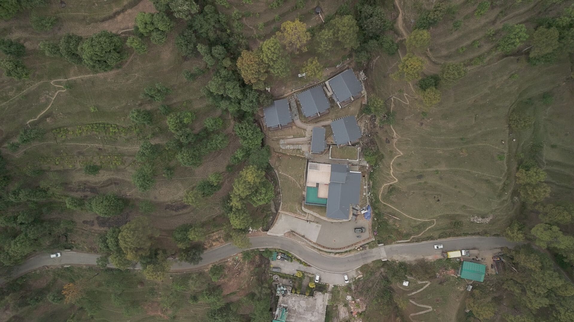 Eine Luftaufnahme eines ländlichen Anwesens mit mehreren Gebäuden, darunter ein Haupthaus mit großer Garage, einem Schwimmbad und einigen kleineren Bauten.