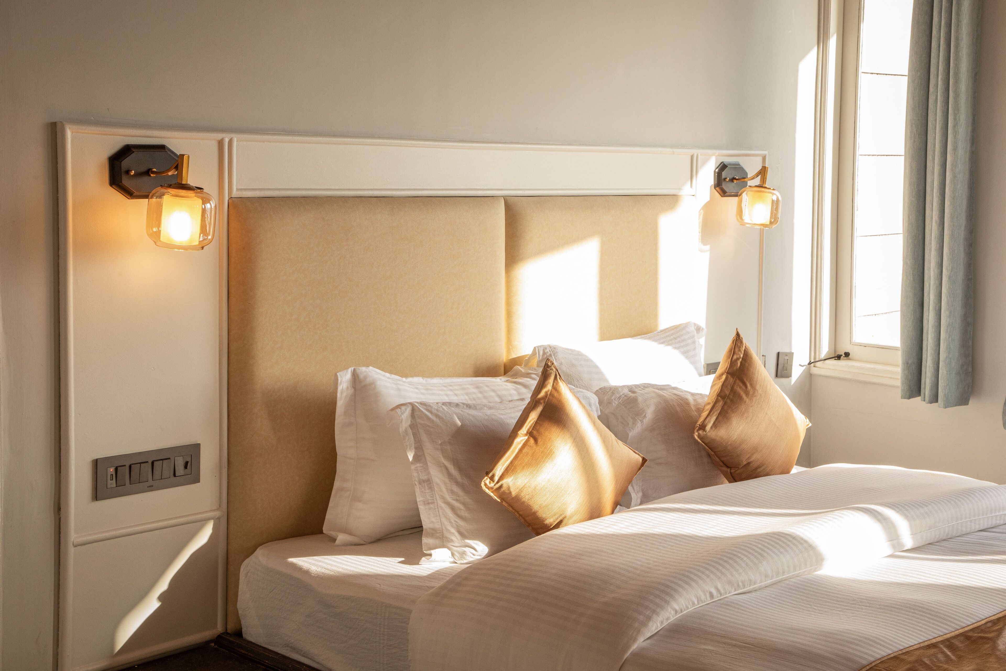 Una habitación de hotel con una cama grande, dos lámparas de pared y una ventana con cortinas.