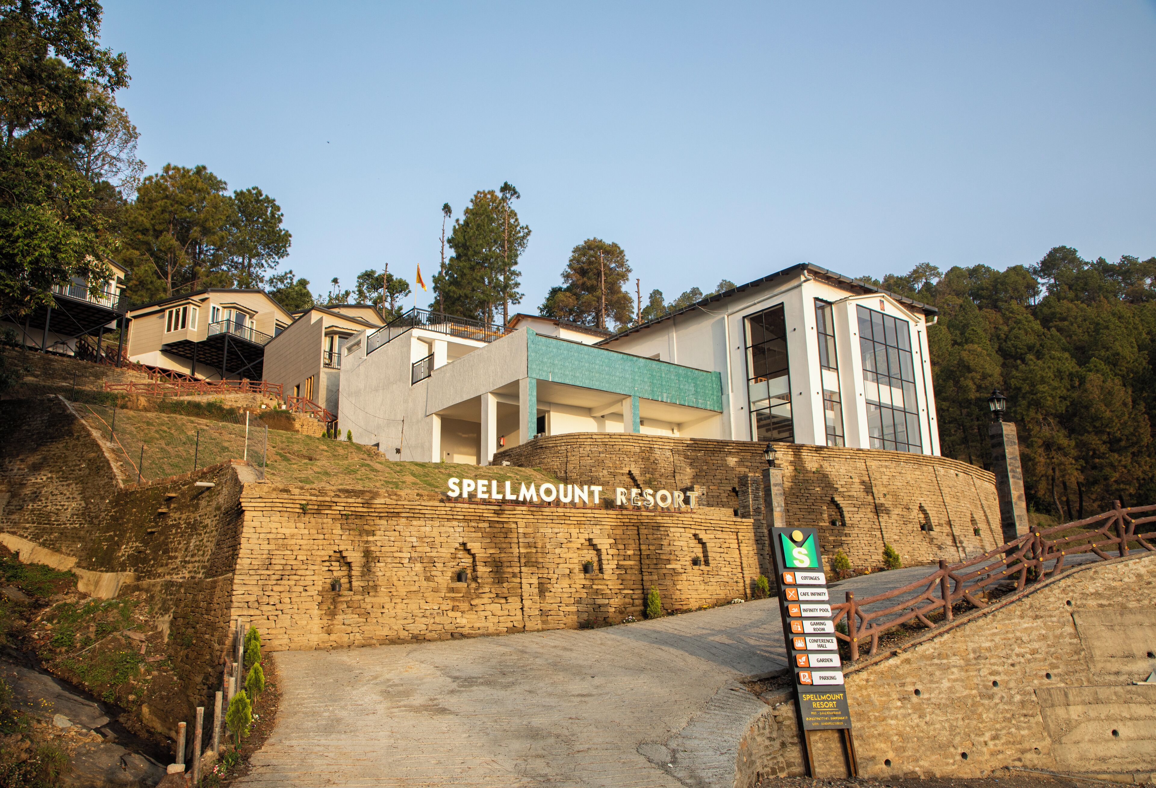 Un resort con un cartel llamativo, un muro de piedra y un camino que lleva a la entrada.