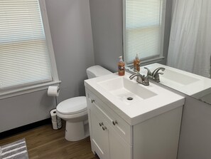 A bathroom with a white sink, mirror, and toilet. There are two bottles on the sink counter. - Prime location:Downtown/Campus (Youngstown)