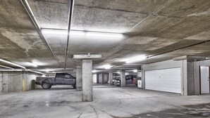 Et parkeringshus med flere niveauer, beton gulve og søjler, samt flere parkerede køretøjer og garageporte.
