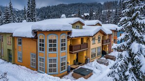 A multi-story building with balconies, large windows, and snow-covered surroundings. - Sun Peaks 67 | Steps from the Village (Sun Peaks)