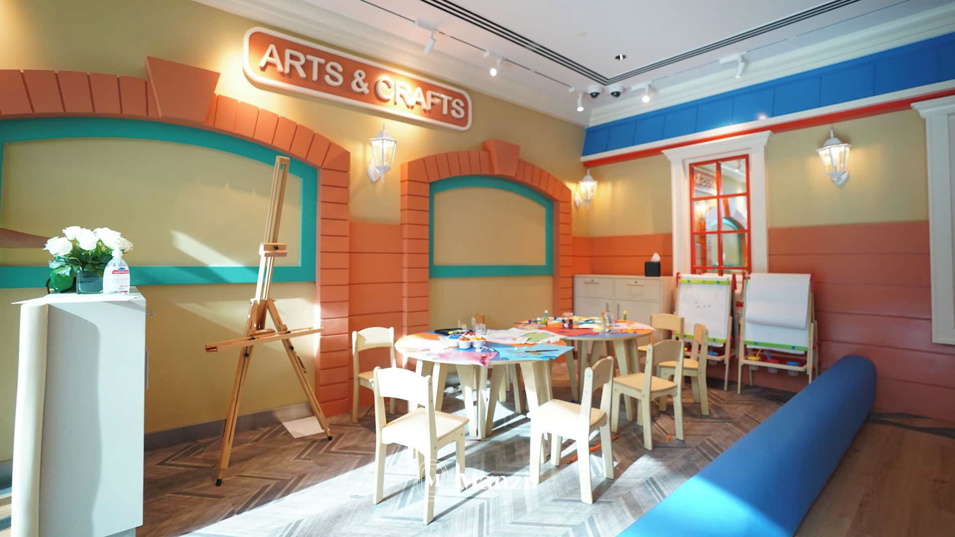 Een kinderkamer voor kunst en knutselwerk met tafels, stoelen, een schildersezel en een whiteboard.