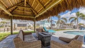 A covered outdoor area with wicker furniture, a fire pit, and a pool. - Lemon Bay Getaway - canal front leading to Lemon Bay and Stump Pass (Englewood)