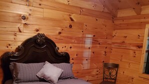 Una habitación con paneles de madera, una cama, una silla y un ventanal.