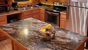 Una cocina con armarios de madera, encimeras de granito, un refrigerador de acero inoxidable y un horno empotrado.