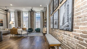 A spacious living area with a brick wall, wooden flooring, and a bench. - Downtown Luxury Condo | Near UT (Knoxville)