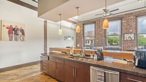 Une cuisine moderne dotée d’un grand îlot central, de meubles en bois et de luminaires suspendus.