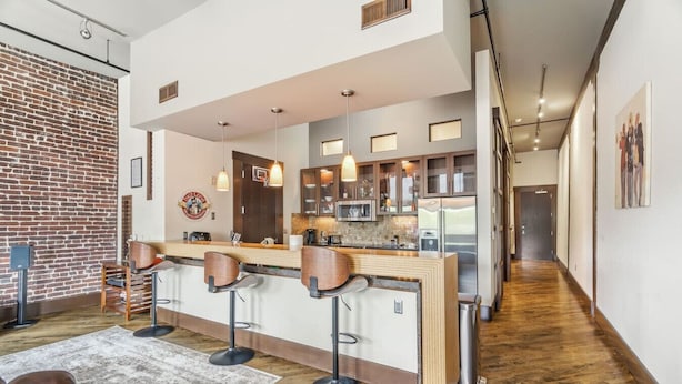 Une cuisine moderne avec un coin bar, un plancher en bois et un mur en briques.