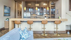 Una cocina moderna con una isla central, taburetes de bar e iluminación colgante.