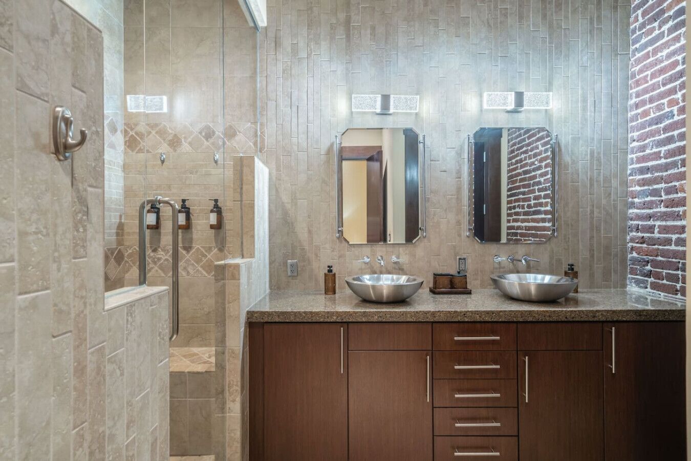 A modern bathroom with two sinks, a shower, and a mirror.