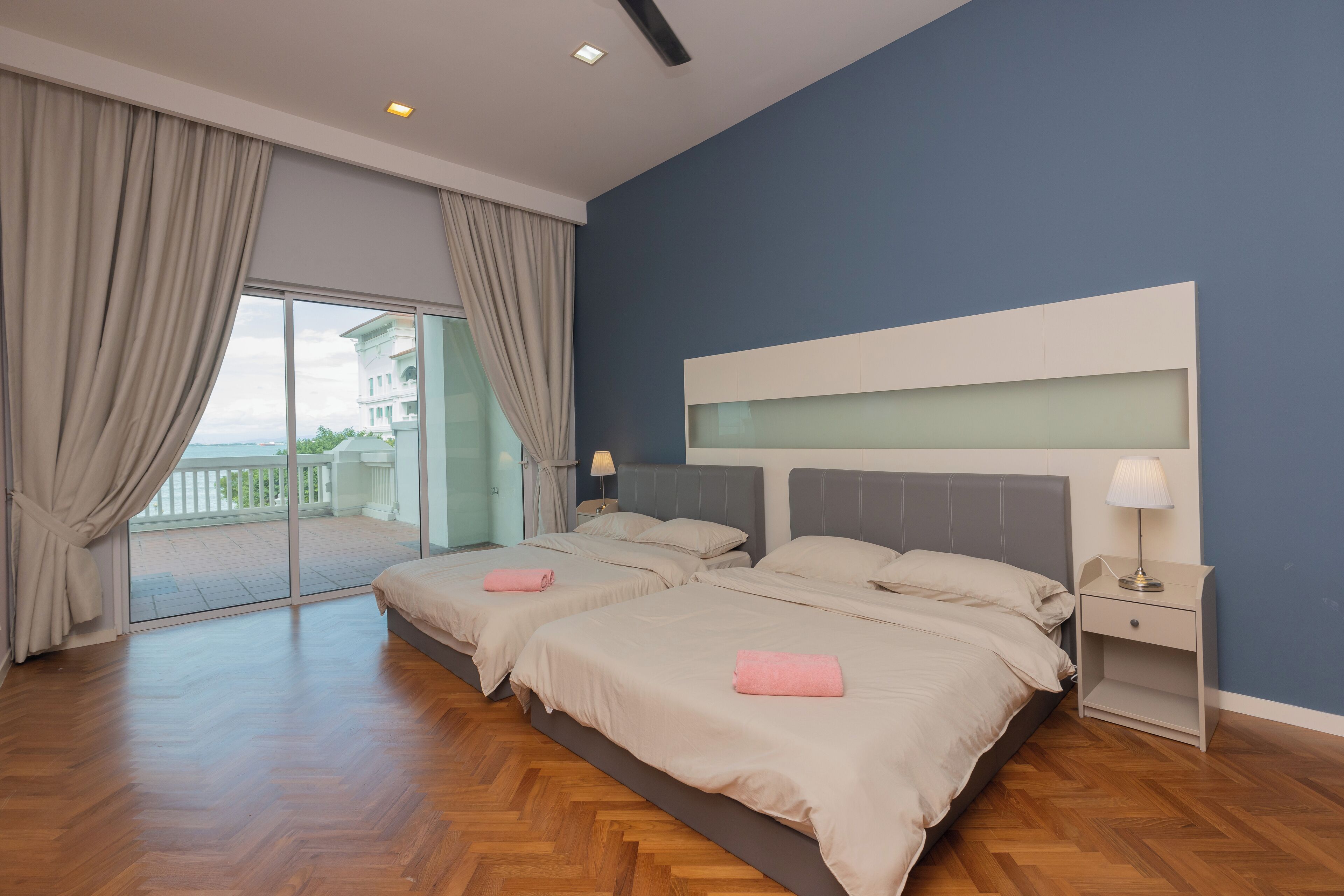 Quarto de hotel com duas camas, uma varanda e vista para um prédio.