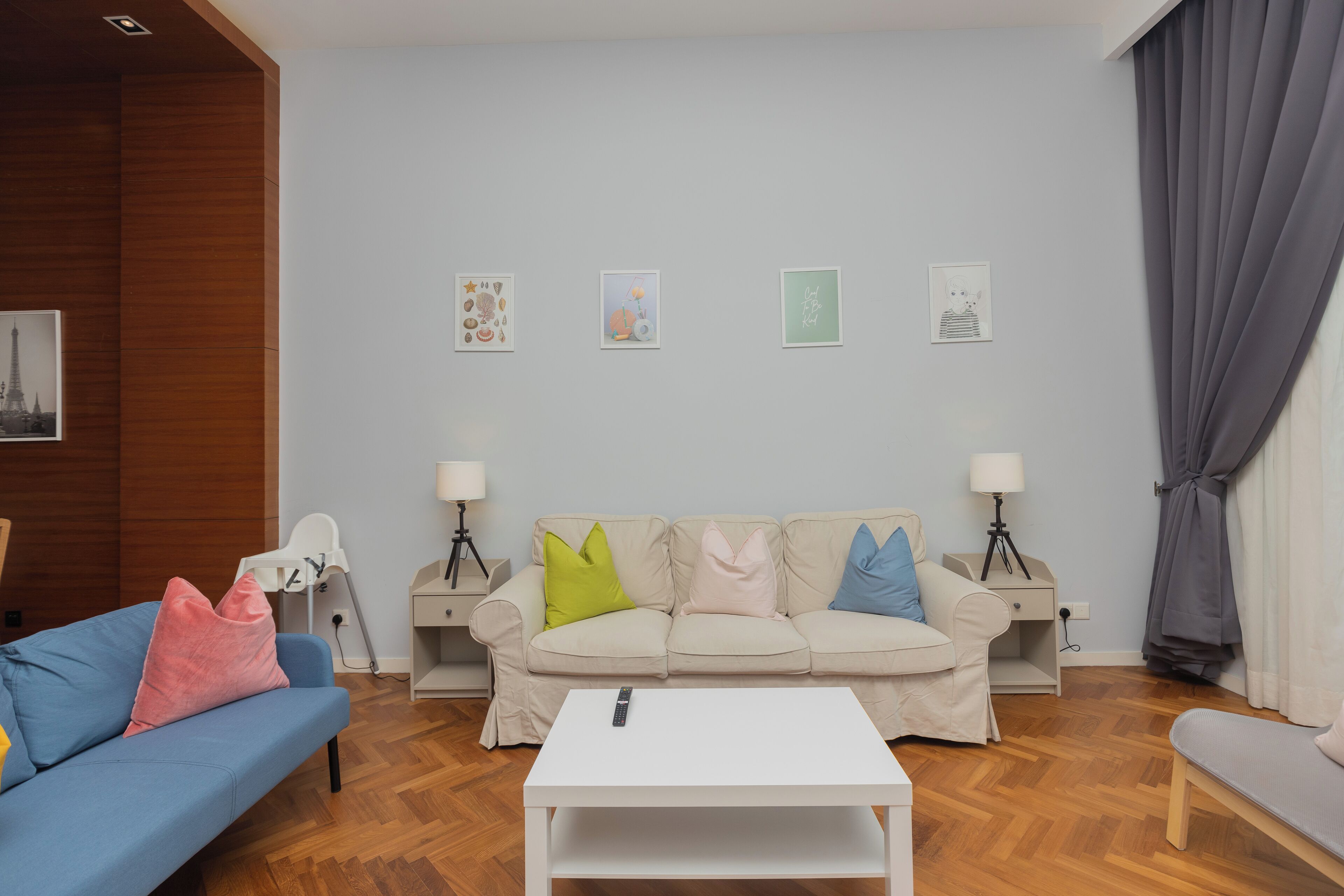 En moderne stue med en beige sofa, farverige puder, et hvidt sofabord og en lampe på hver side.