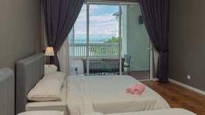 Ein Schlafzimmer mit Bett, Nachttisch mit Lampe und Blick auf einen Balkon mit Tisch und Stühlen.