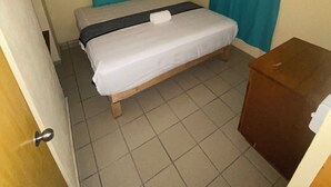 Una habitación pequeña y sencilla con una cama, un ventilador de techo y un armario de madera.