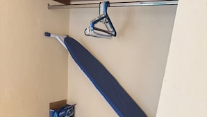 Una habitación pequeña con un escritorio de madera, un perchero, una mesa de vidrio y una caja de pañuelos.