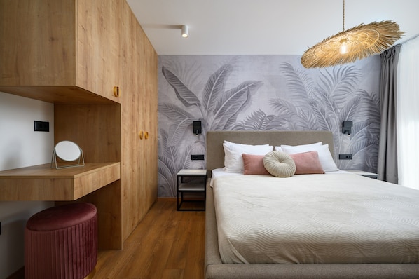 Une chambre à coucher avec un lit, une armoire en bois, une petite table de chevet, un tabouret rouge et un mur orné d’un motif de feuilles.