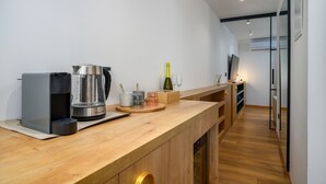 Une cuisine moderne avec une machine à café, une bouteille de vin et un verre à vin posés sur le comptoir.
