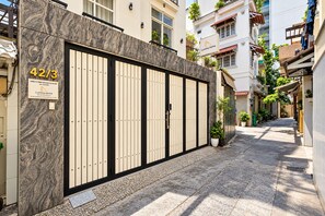 A gated entrance with a marble facade, a sign indicating the property name, and a narrow alleyway with buildings on either side. - Lumina Home (Ho Chi Minh City)