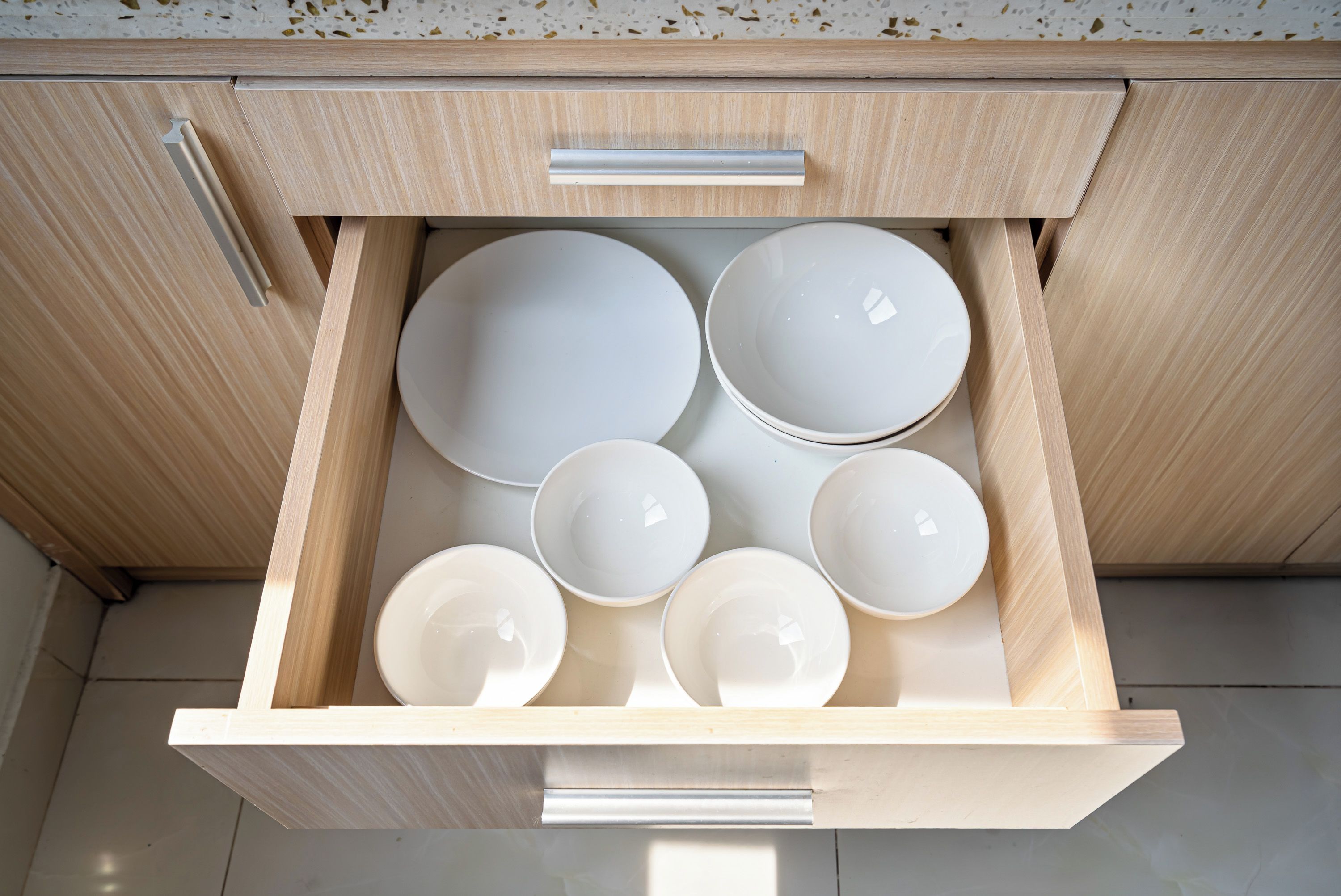 A drawer with multiple white bowls and plates.