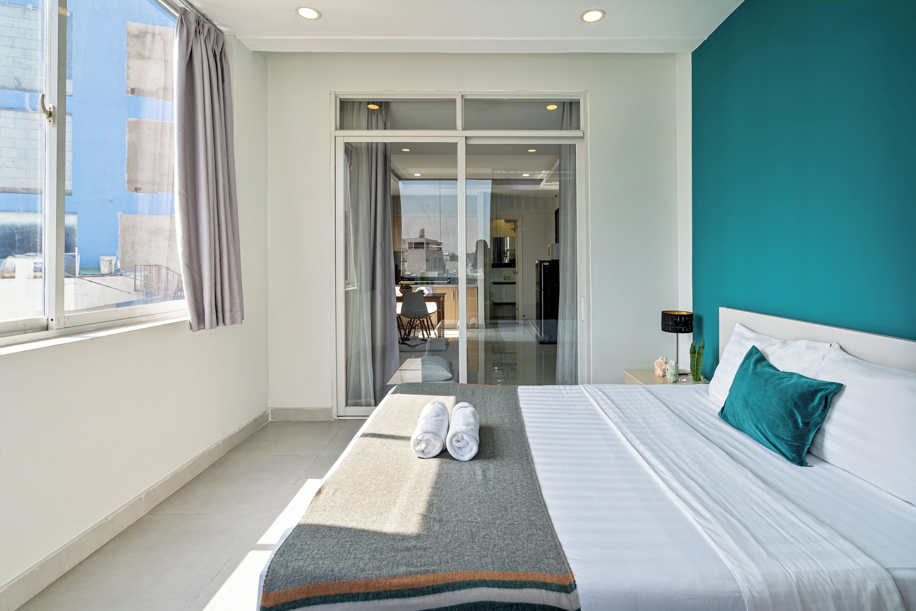 A hotel room with a bed, a bathroom, and a view of the city.