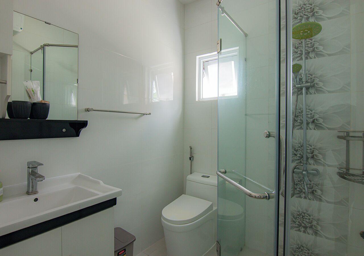 Un baño con cabina de ducha de vidrio, un lavamanos blanco y un inodoro.