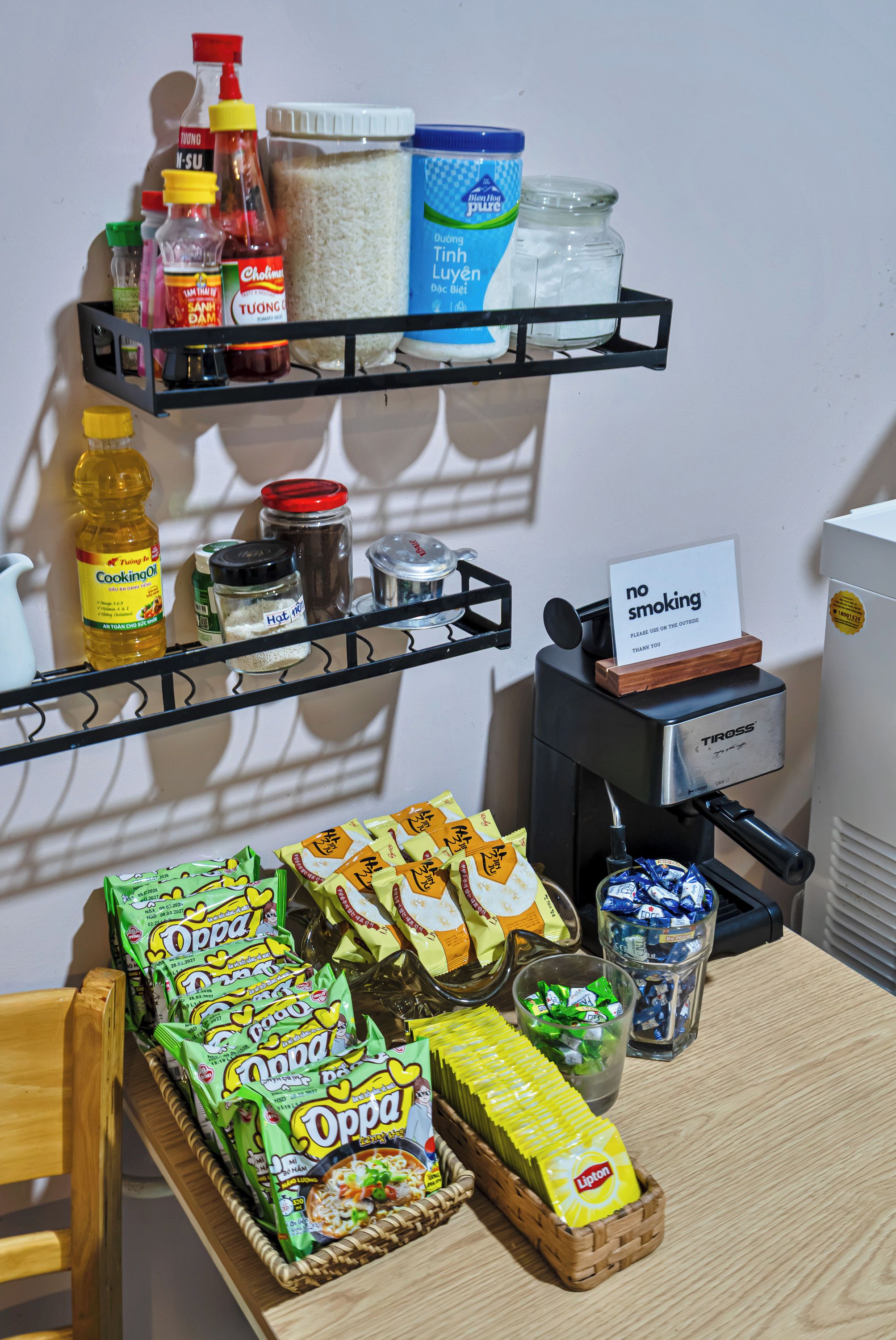 A kitchen area with shelves holding condiments, cooking oil, and food items.