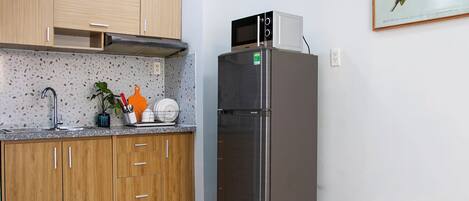 Una cocina con armarios de madera, un refrigerador de acero inoxidable, un microondas y un lavamanos.