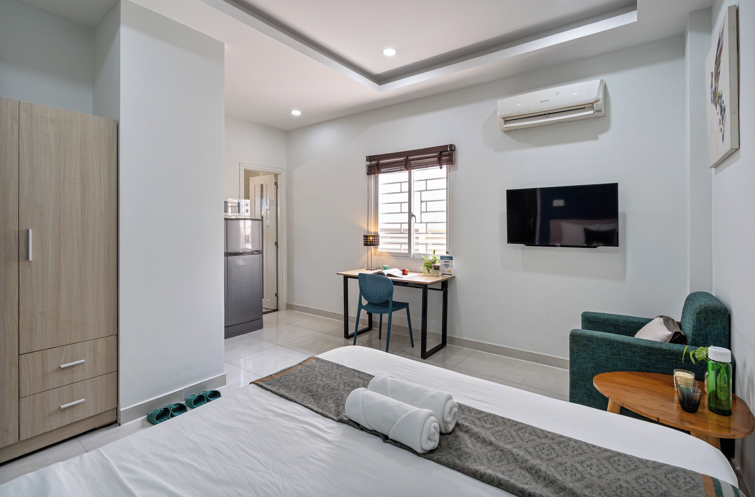 Una habitación de hotel con cama, escritorio, silla, televisor y armario.