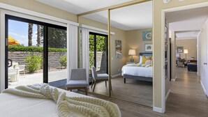 Una camera da letto con un grande specchio, un letto con copriletto bianco, una sedia e vista sull'esterno.