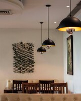 Un comedor con una mesa, sillas, lámparas colgantes y una planta en la pared.
